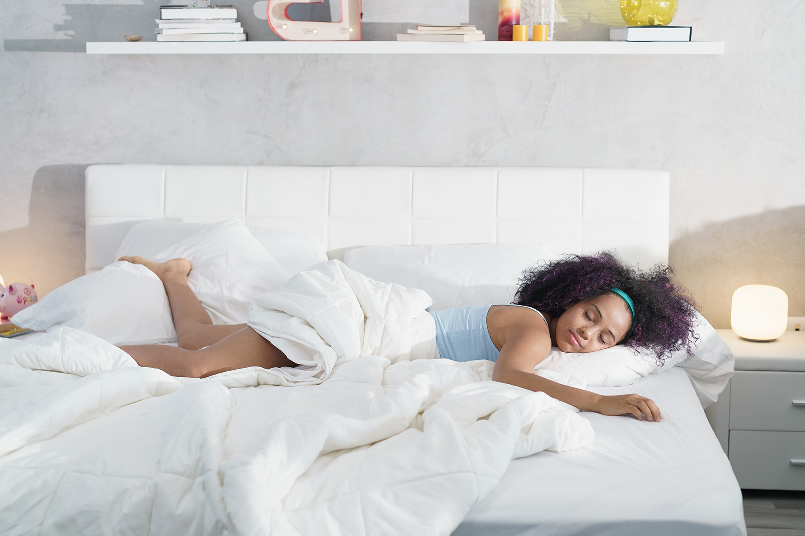 MRArticleMovingYourMattress1 MattressReviewscom Image of a woman lying on a bed partially covered by a blanket