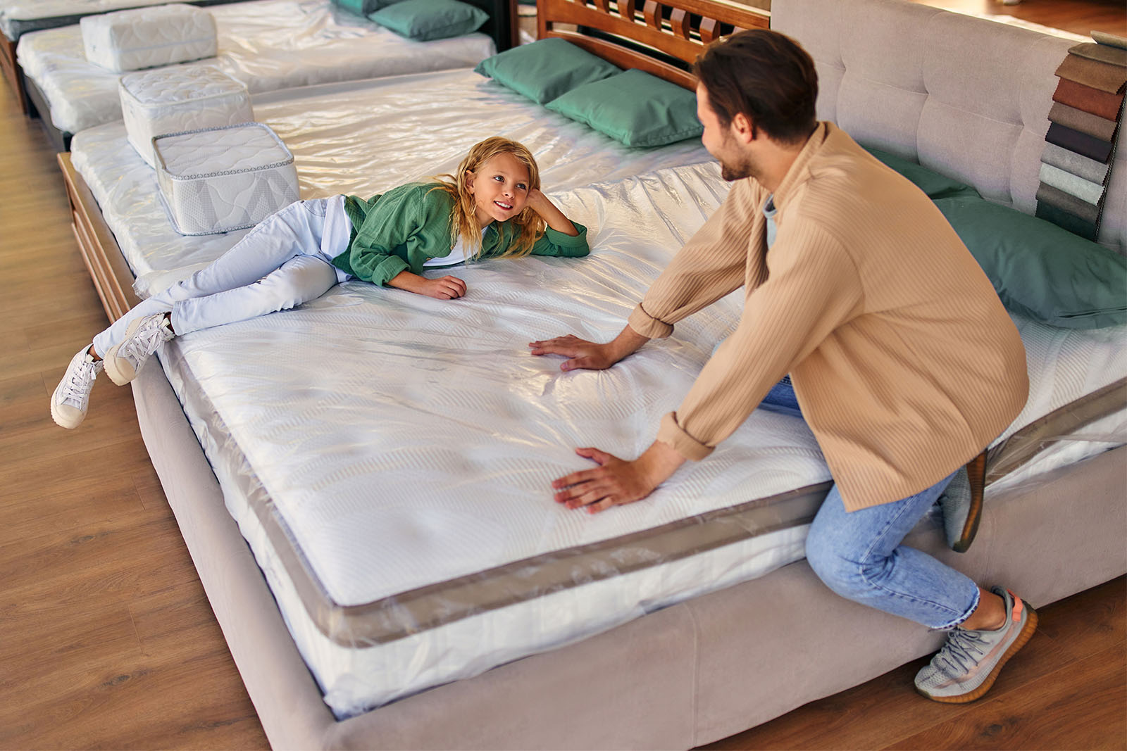 MRArticleOnlineInstore 2 MattressReviewscom A father and his daughter at a mattress store lying down and pressing on the mattress