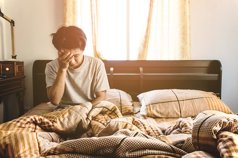 articleenvironmentallyfriendly2 MattressReviewscom Canadians Will Pay More for Environmentally Friendly Sleep Products hero image photo of a person sitting up in bed looking tired